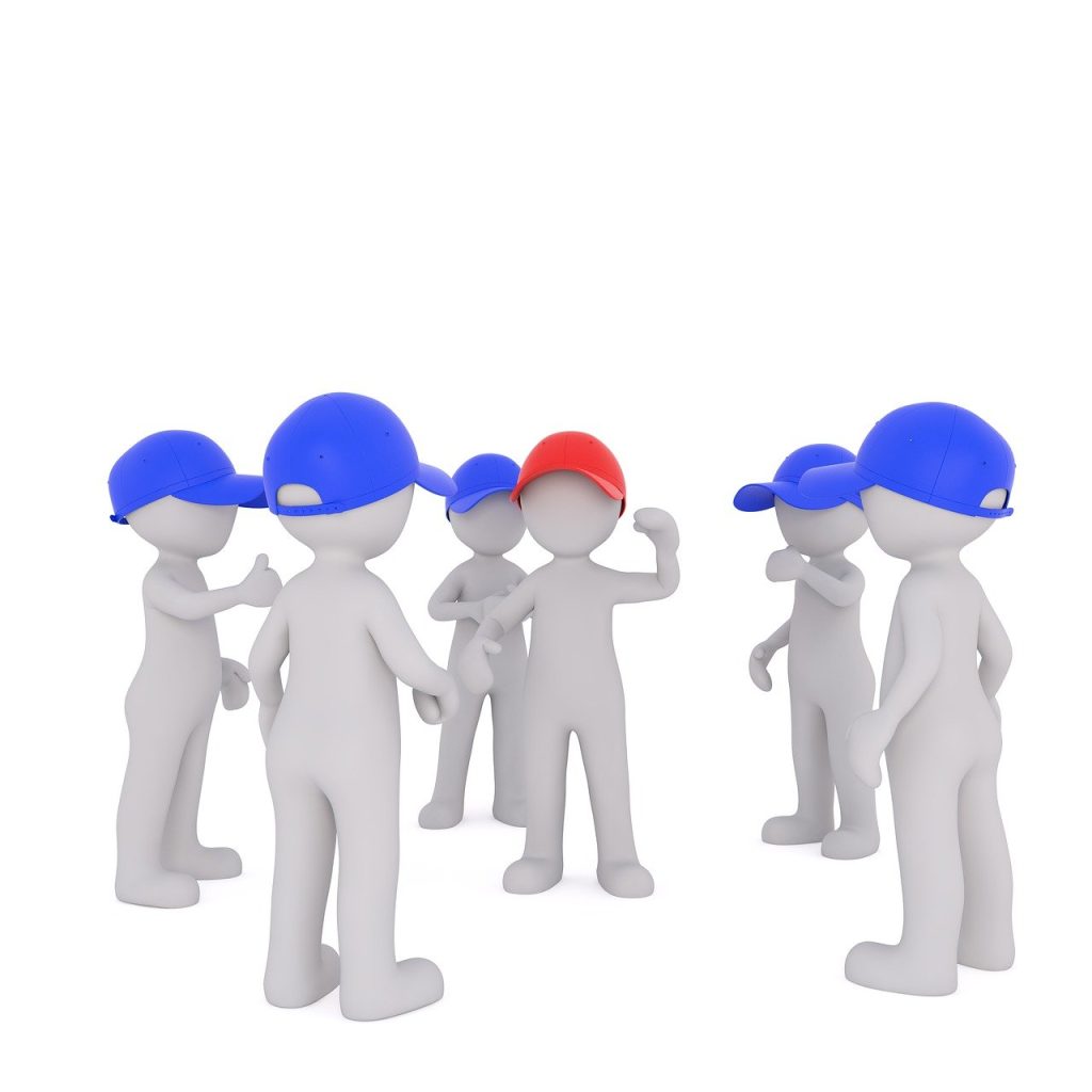 Gruppe von grauen Figuren mit blauen Kappen umkreisen eine Figur mit einer roten Kappe.
